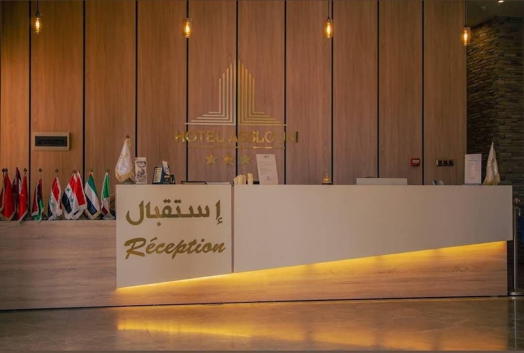 Hotel Asslouni reception with warm wood and gold signage